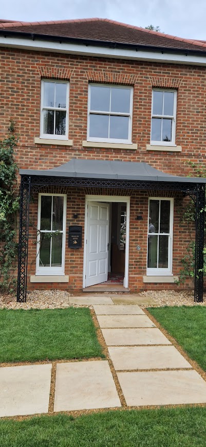 A finished brick-built home with new porch canopy and sandstone paved path, completed by Da Silva Building Construction